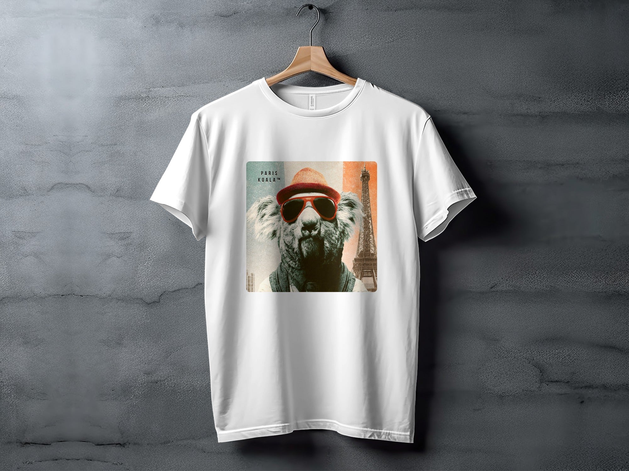 White t-shirt with a graphic of a koala wearing sunglasses and a hat with the Eiffel Tower.
