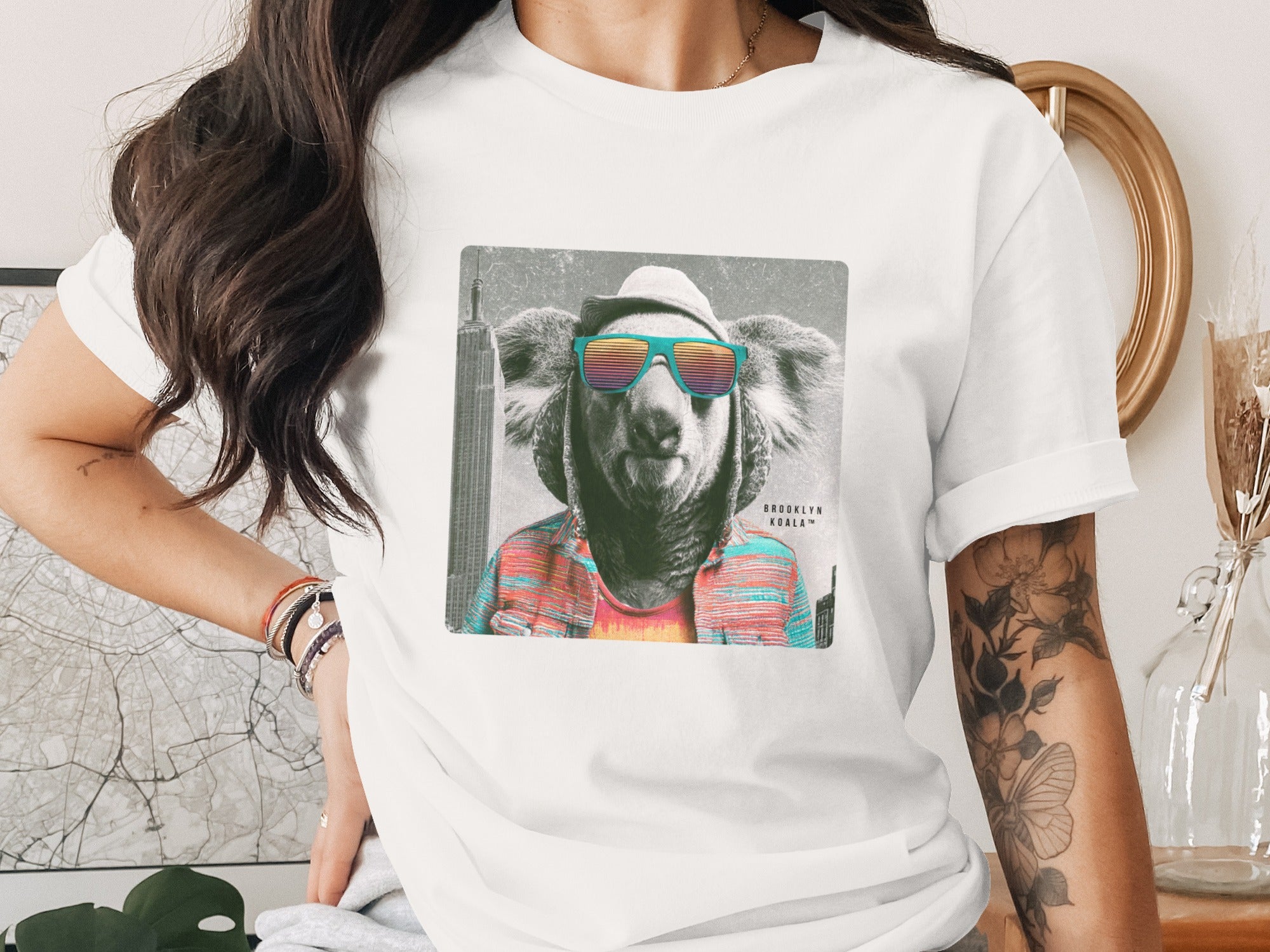 T-shirt with a koala wearing sunglasses and a hat, with cityscape background.