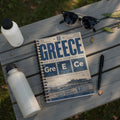 Notebook with "GREECE" and football-themed elements, listing cities and values.