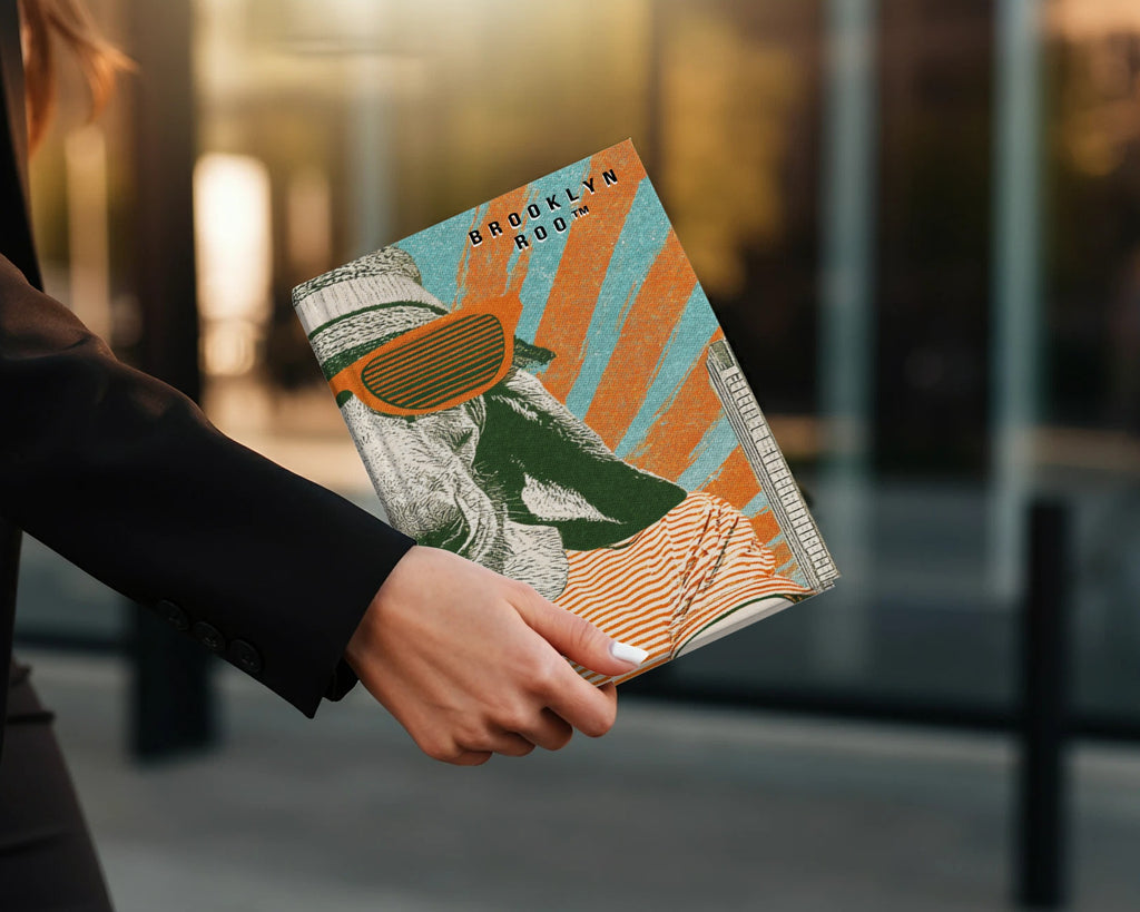 Woman holding a book with colorful stripes and "Brooklyn Roo" text.