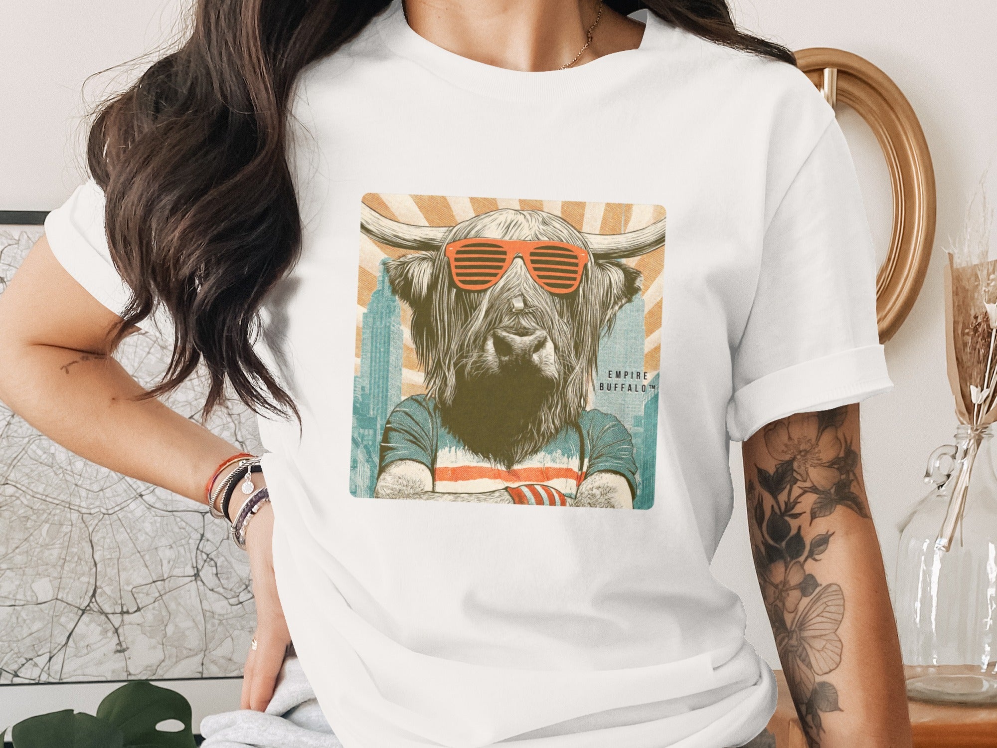 Highland cow wearing sunglasses and a t-shirt with "Empire Buffalo" text.