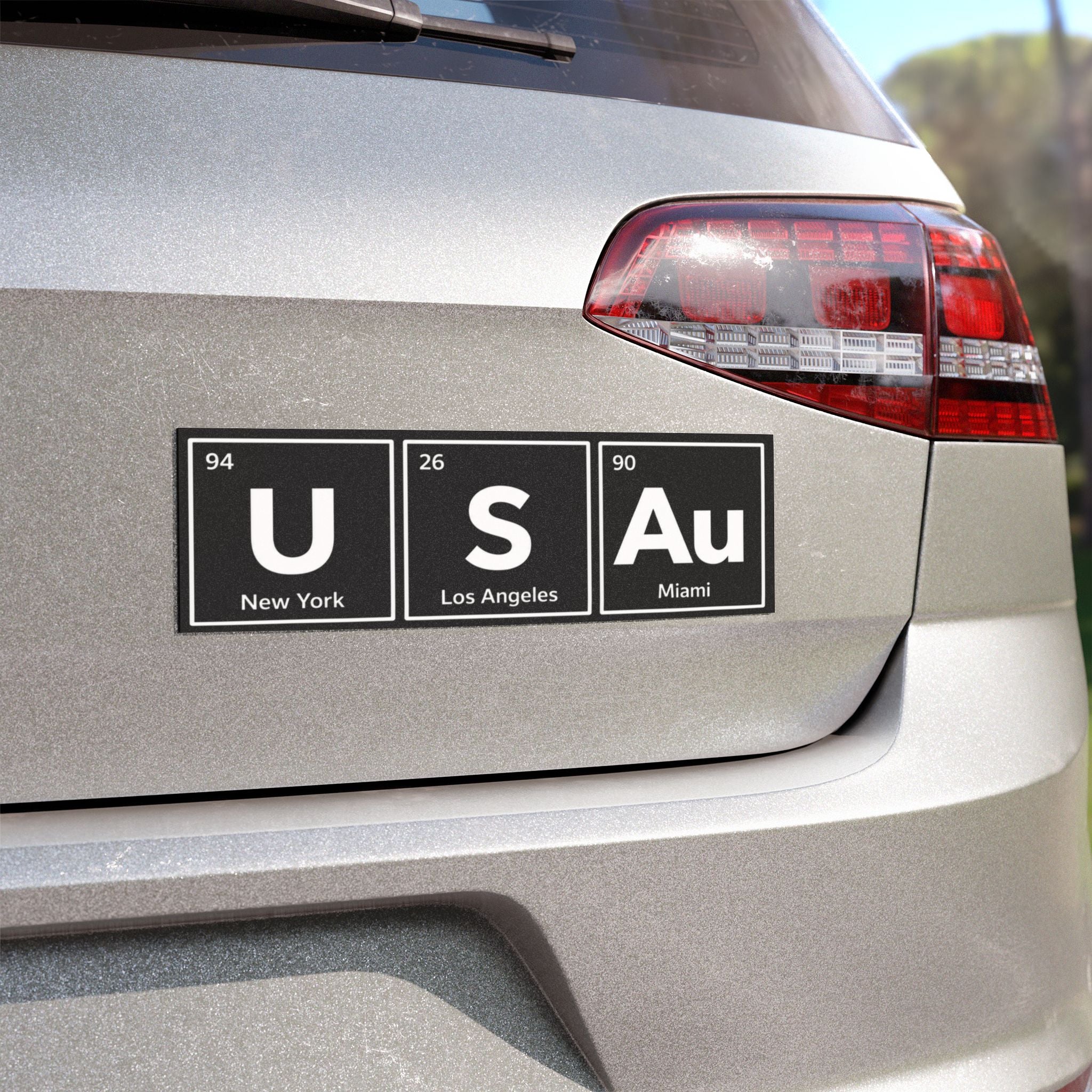 Car bumper sticker with "USA" spelled using periodic table elements.