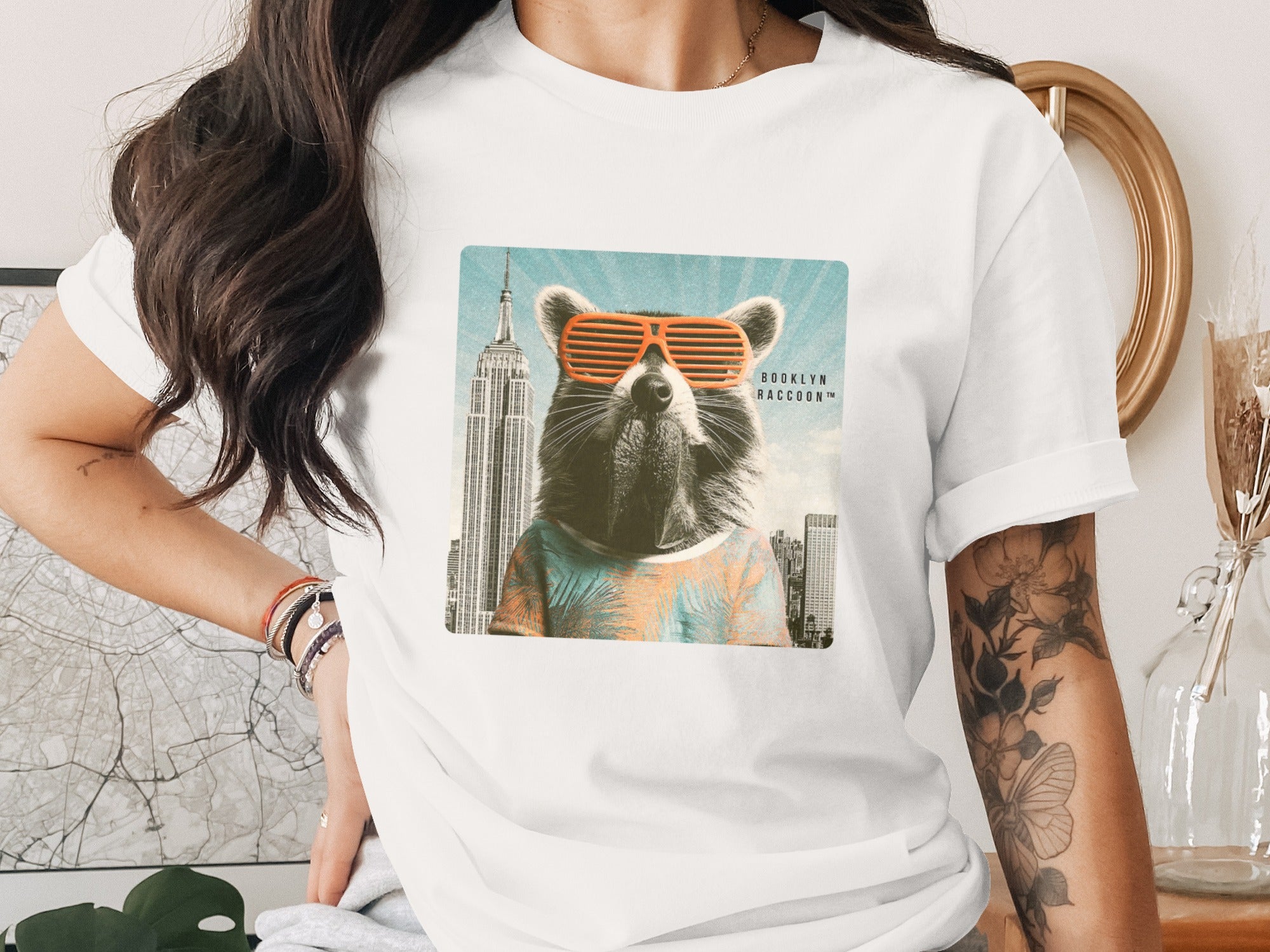 T-shirt with graphic of a raccoon in sunglasses and Hawaiian shirt with city skyline.
